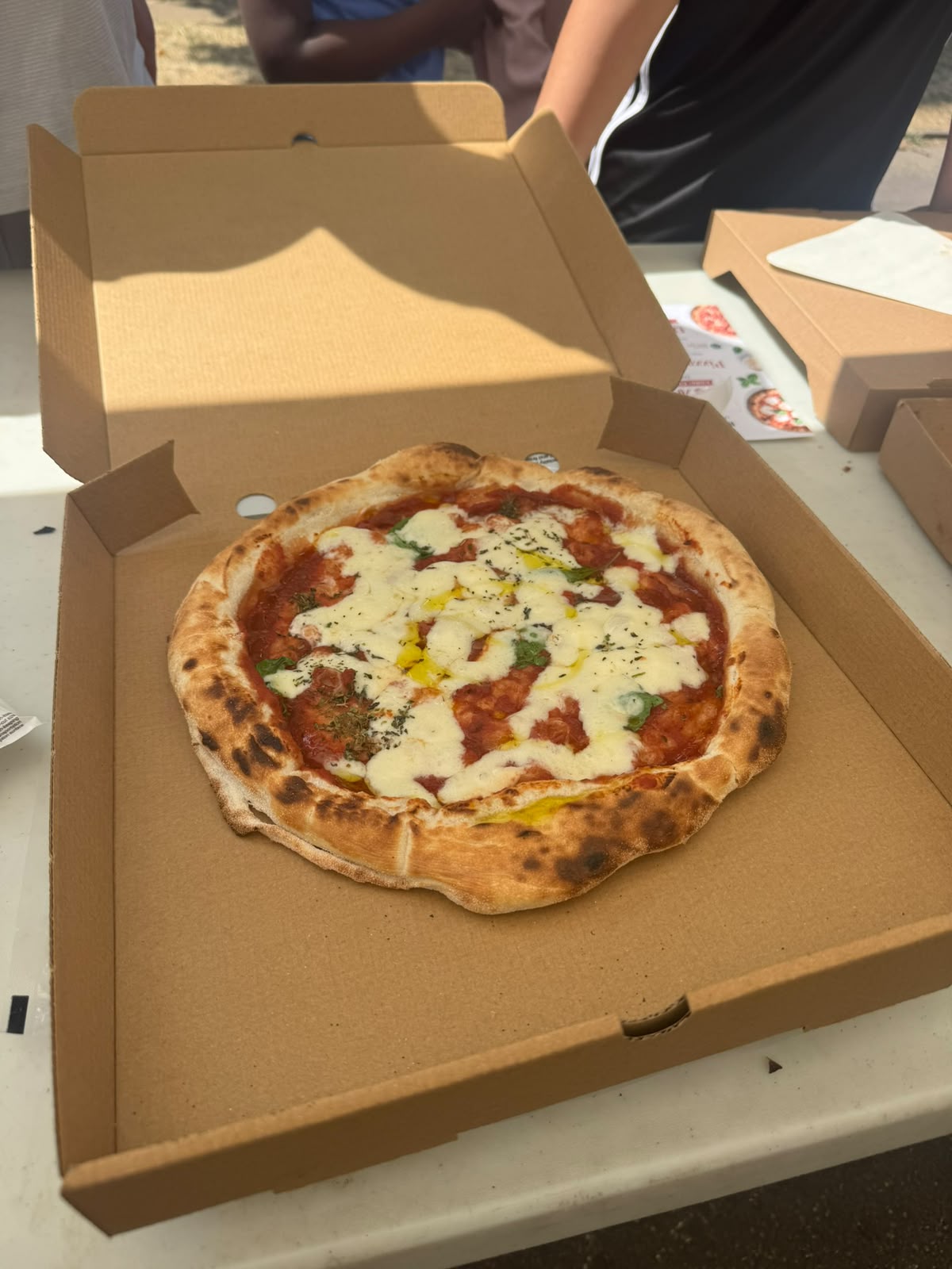 Whole tomato and mozzarella pizza in an open takeaway box
