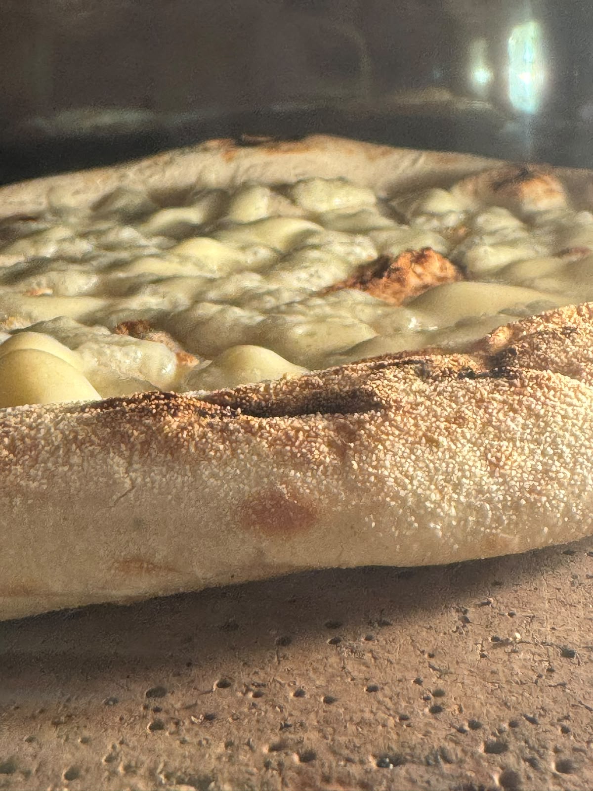 Close-up of a golden pizza crust baking in the oven